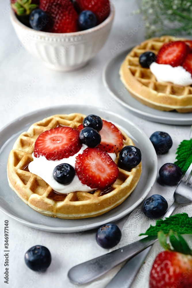 Homemade mini Waffles topped with fresh berries and cream, selective focus Homemade mini Waffles topped with fresh berries and cream, selective focus