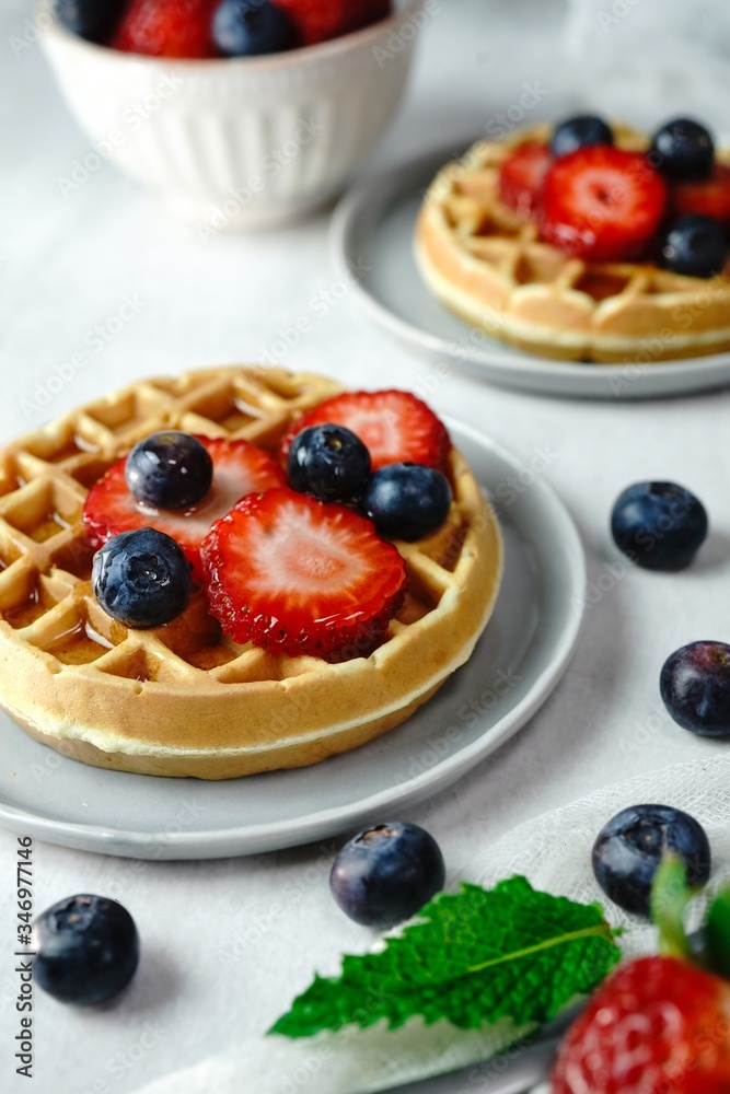 Homemade mini Waffles topped with fresh berries and cream, selective focus Homemade mini Waffles topped with fresh berries and cream, selective focus