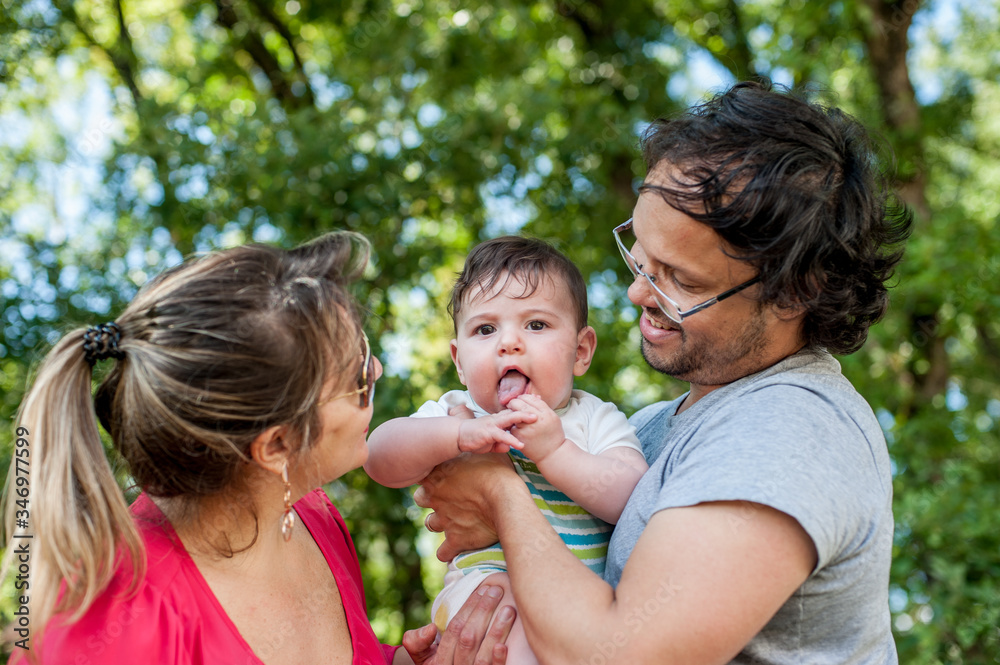 Front view of happy parents playing with their baby in the park. Front view of happy parents playing with their baby in the park.
