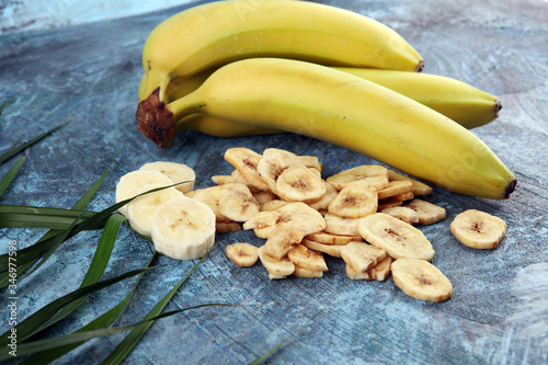 Homemade Dehydrated Banana Chips and fresh banana and slices on background