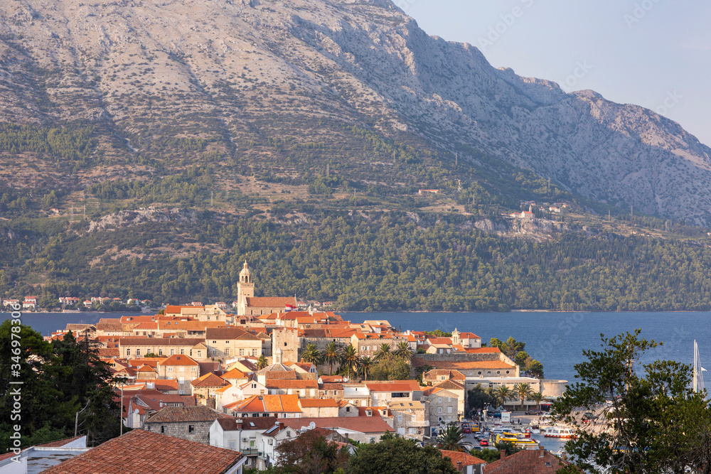 Korcula island with the cathedral, the city and the port on a sunny day during sunset in summer. Beautiful old venetian architecture, trees and mountains creating an idyllic scenery