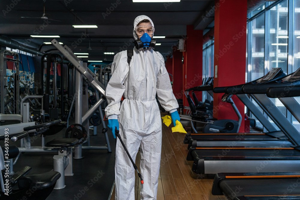Cleaning and Disinfection in crowded places amid the coronavirus epidemic Gym cleaning and disinfection Infection prevention and control of epidemic. Protective suit and mask and spray bag COVID-19