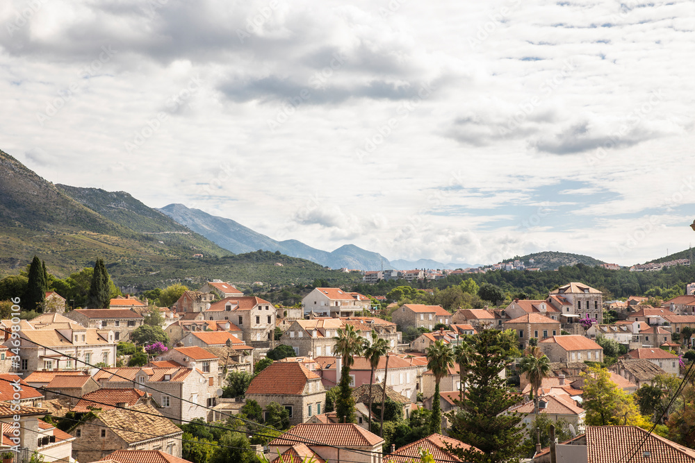 View over Cavtat with it’s white houses and orange roofs and the beautiful mountains and greenery in the background on a cloudy day in summer