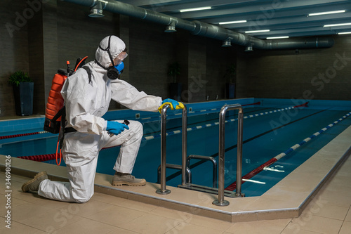 Cleaning and Disinfection in pool amid the coronavirus epidemic Gym cleaning and disinfection Infection prevention and control of epidemic. Protective suit and mask and spray bag COVID-19