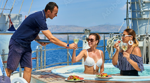 Young beautiful girls relax on board a sailing yacht. Exclusive service aboard the ship