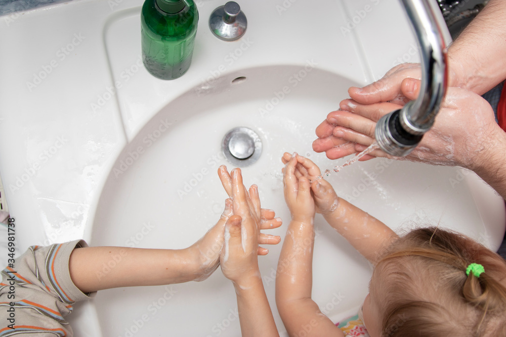 Fototapeta premium prevention of viruses. dad with son and daughter washing of hands soap foam and water. Disinfection against bacteria and viruses, protection against covid-19 disease.
