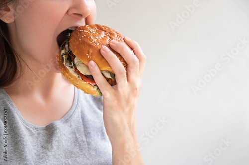 Vegan burger closeup in girl hands. Happy woman tasting and biting burger