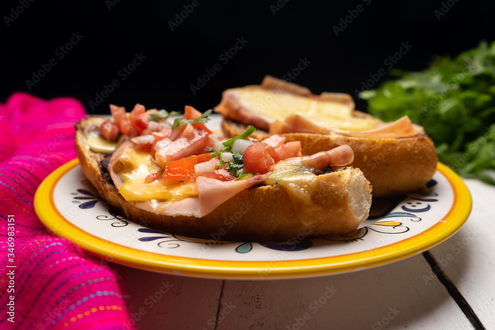 Mexican molletes with ham and cheese on dark background Mexican molletes with ham and cheese on dark background