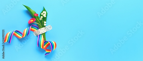 Thank you doctors and nurses! Rainbow ribbon and bouquet of red primrose and lily of the valley flowers attached with medical aid patch. Creative panoramic flat lay on blue background, text space. photo