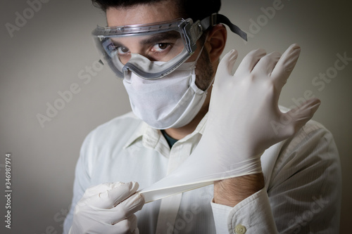 Homem caucásio branco brasileiro em fundo branco usando mascara e luva e óculos de segurança equipamento de proteção individual médico ou doutor em Combate ao Coronavírus photo
