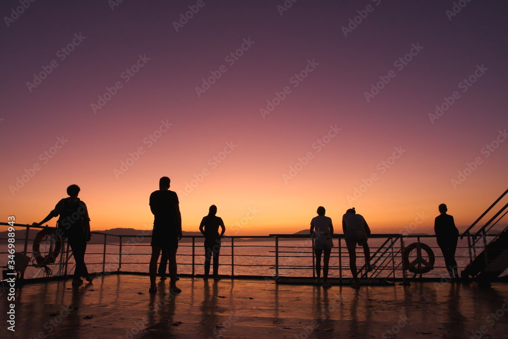 silhouettes of people against the background of the sunset over the sea