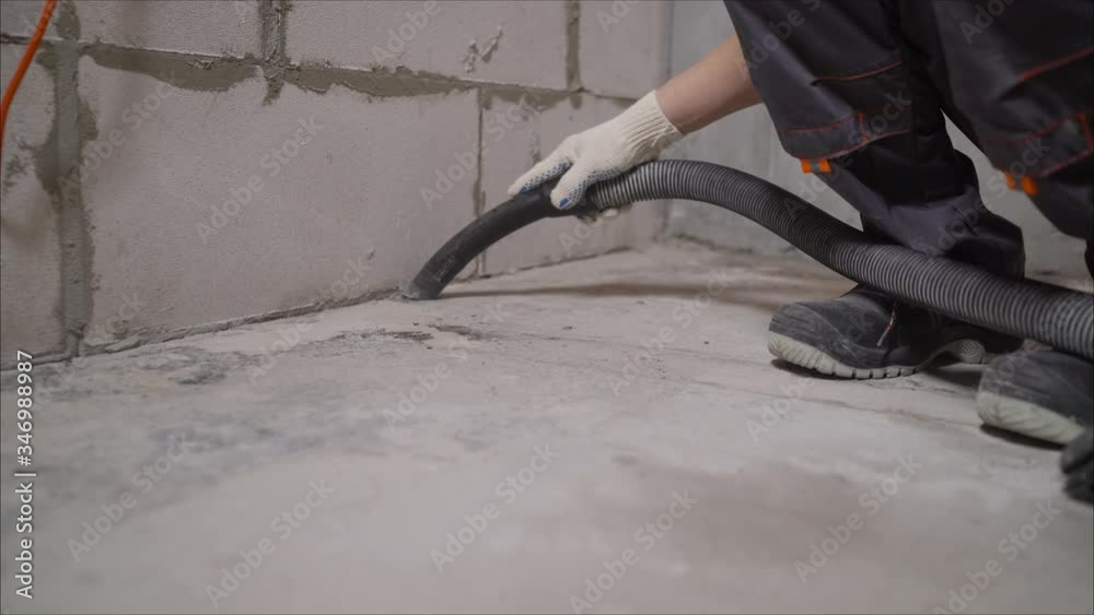 Man Vacuuming a Construction Site. Closeup of a cleaner in special clothes and rubber gloves holds a brush from an industrial professionally vacuum cleaner. Man Vacuuming a Construction Site. Closeup of a cleaner in special clothes and rubber gloves holds a brush from an industrial professionally vacuum cleaner.
