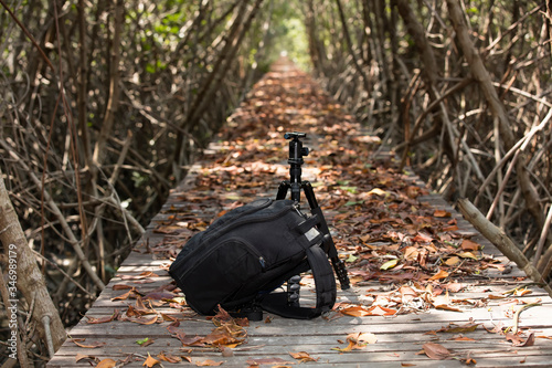 Camera bag black with tripot stand on wooden footpath bridge  photo