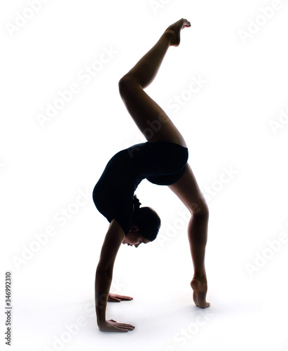 Graceful gymnast in sportswear performs a handstand. Training, element of gymnastics, acrobatics on a white background. Sports motivation, stretching
