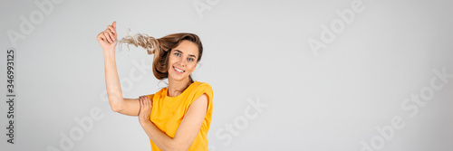 Web banner of a beautiful woman on a white background twisting her hait on the fingure, empty space