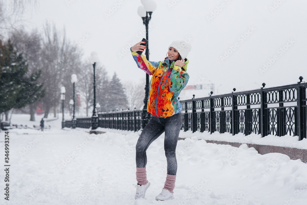A young athletic girl takes a selfie on a frosty and snowy day. Fitness, recreation
