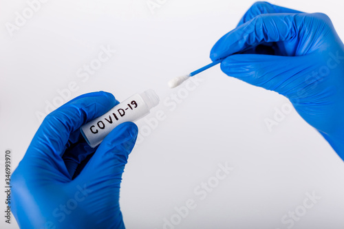 A healthcare professional takes a smear of COVID-19. In protective gloves. Test tube for analysis. Doctor with test tube for analysis and sampling of infection. Side view. White background.