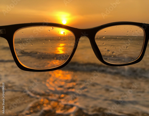 A pair of glasses at the beach with the sunset and how unclear life is to a person without a pair of glasses