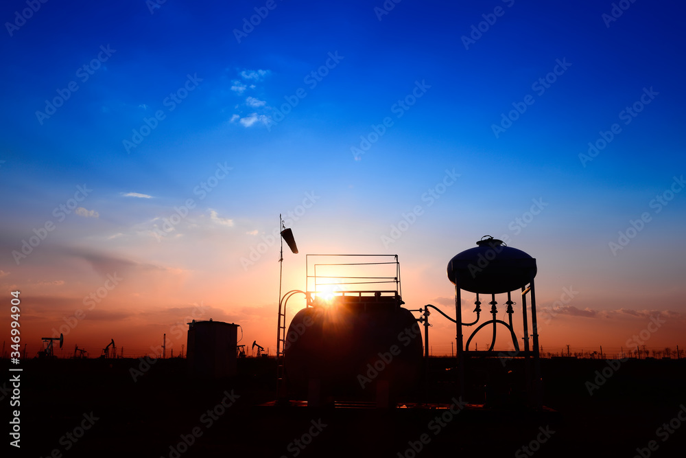 Oil tanks, silhouetted against the setting sun