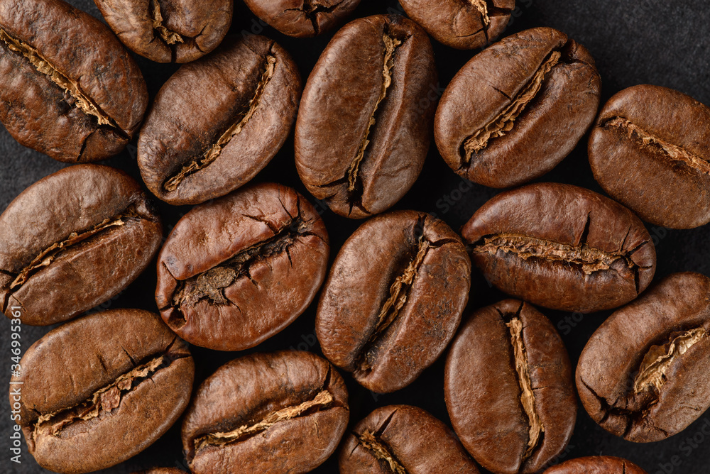 Fototapeta premium Roasted coffee beans on a black background, detailed macro.