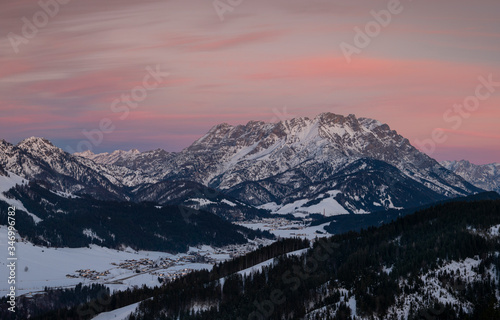 Mountains of mountain range Wilder Kaiser at Fieberbrunn during sunset in winter with snow, forest and valley, clouds in the sky, Tyrol Austria. photo