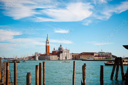 Traditional European architecture. The view of the Church of San Giorgio Maggiore with an antique bell tower near a grand canal with boats (gondolas) and the St. Marks Square in Venice, Veneto, Italy.