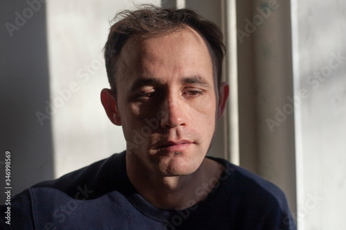 Portrait of a guy in natural light. The face of supper in the early morning. European type of face. Brown eyes and sleepy face. A simple moment of life. Adult man looking at the camera.