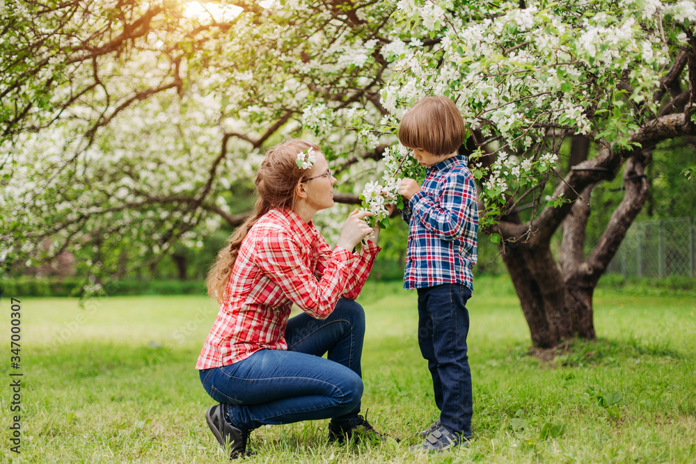 Mother and baby in blooming garden. Mom and child in spring. Springtime family scene. Flowers of apple or cherry tree. Mother and baby in blooming garden. Mom and child in spring. Springtime family scene. Flowers of apple or cherry tree.