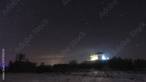 Timelapse night sky stars. Olesko castle at winter night. photo