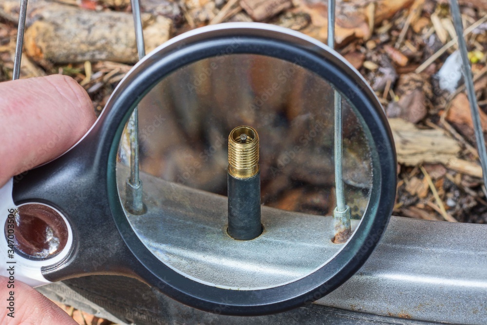 black magnifier in hand increases metal nipple on bicycle wheel black magnifier in hand increases metal nipple on bicycle wheel