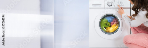Woman Pressing Button Of Washing Machine photo