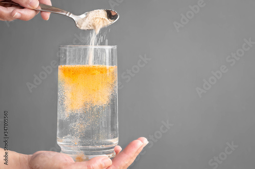 Orange fizzy powder and water glass with copy space. Healthy supplement.