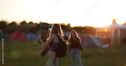 Vintage long haired caucasian girls at festival camping site in sunset throwing camping gear op in the air in slow motion