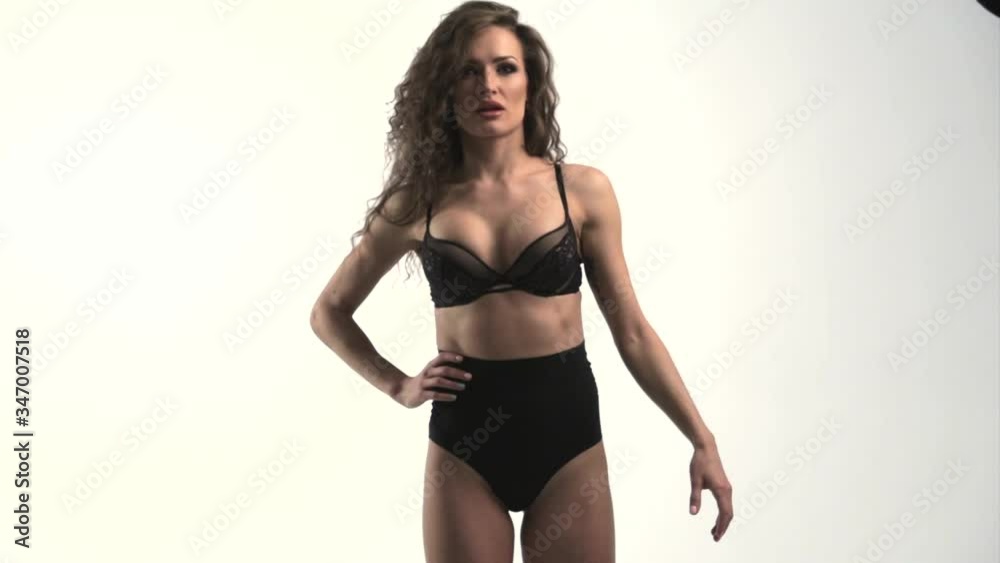 The young beautiful woman with curly hair poses, wriggles and flirts in front of a camera, Sexual underwear of black color, a white background, is dancing, she coquets, Different emotions on a face The young beautiful woman with curly hair poses, wriggles and flirts in front of a camera, Sexual underwear of black color, a white background, is dancing, she coquets, Different emotions on a face