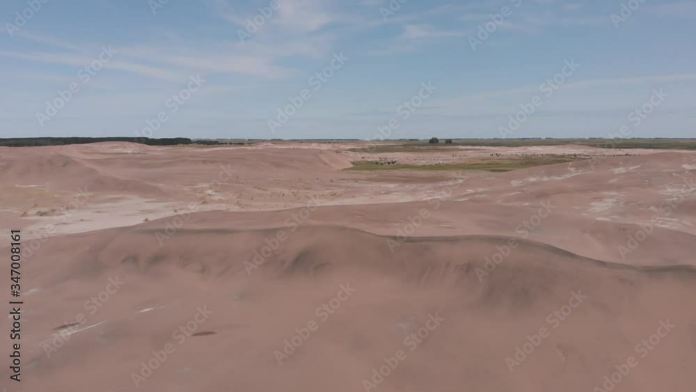 Aerial view over the dunes and on the horizon a view of more dunes, vegetation and trees. Descent until the horizon disappears. The sky with some clouds Aerial view over the dunes and on the horizon a view of more dunes, vegetation and trees. Descent until the horizon disappears. The sky with some clouds