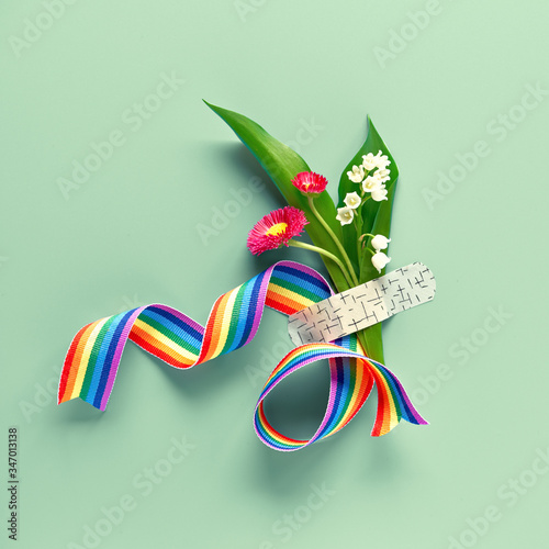 Thank you doctors and nurses! Rainbow ribbon and bouquet of red primrose and lily of the valley flowers attached with medical aid patch. Creative flat lay on mint green background, square composition. photo