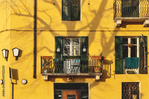 Empty sunlit balcony on traditional Italian house with shadow of tree, Verona, Italy