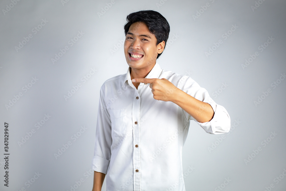 Smiling guy. Portrait of excited and happy young Asian man pointing copy space on gray background. Young Asian business man. Smiling guy. Portrait of excited and happy young Asian man pointing copy space on gray background. Young Asian business man.