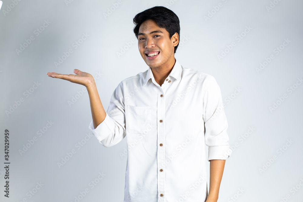 Smiling guy. Portrait of excited and happy young Asian man present something on gray background Smiling guy. Portrait of excited and happy young Asian man present something on gray background