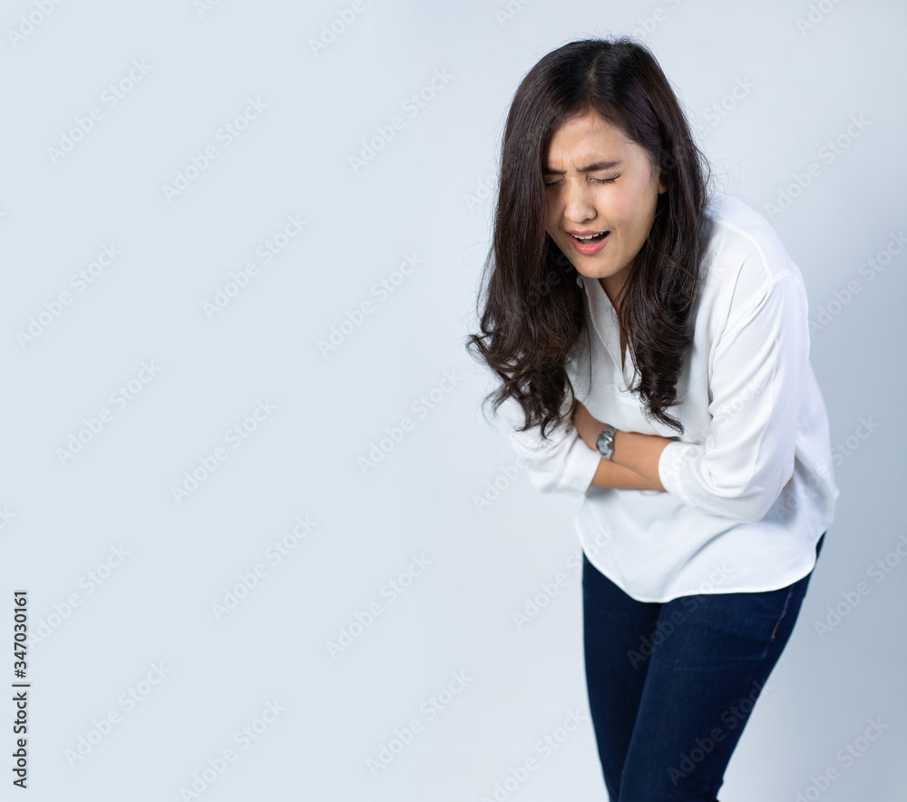 Sick Asian woman having a stomach ache on white background. Female holds hands on abdomen Sick Asian woman having a stomach ache on white background. Female holds hands on abdomen