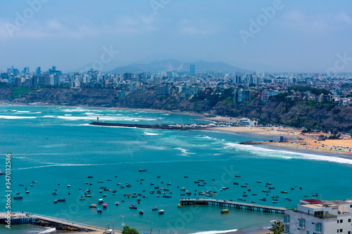 Aerial view of the beach in the city of Lima, Peru. Some docks and boats on the blue sea
