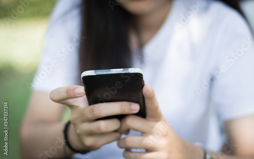 Asian woman using,working by smartphone at park,soft focus.