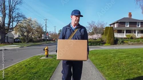 An impatient mail carrier delivers a cardboard box to a suburban home by drop kicking it.