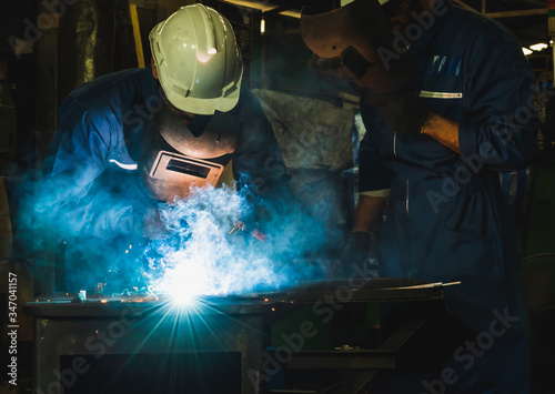 Industrial worker welding metal with many sharp sparks