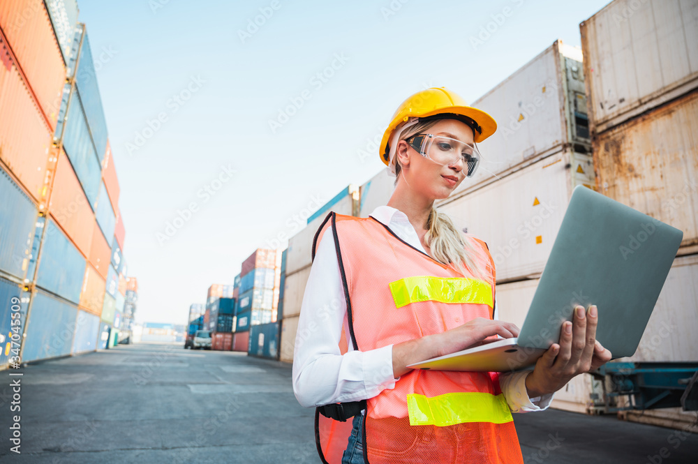 Foreman woman worker working checking at Container cargo harbor holding laptop computer to loading containers. Dock female staff business Logistics import export shipping concept. Foreman woman worker working checking at Container cargo harbor holding laptop computer to loading containers. Dock female staff business Logistics import export shipping concept.