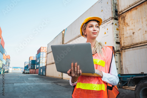 Foreman woman worker working checking at Container cargo harbor holding laptop computer to loading containers. Dock female staff business Logistics import export shipping concept.