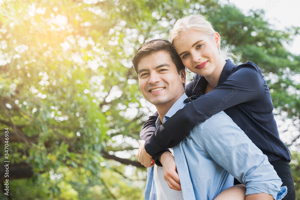 Boyfriend carrying his girlfriend in park. Wife is riding on back husband romantically. Boyfriend carrying his girlfriend in park. Wife is riding on back husband romantically.