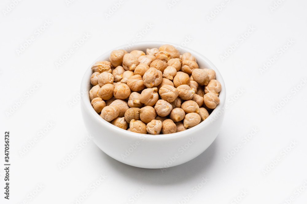 Chickpeas bowl on white background. These uncooked chickpeas are common staple food ingredients. Also called pulses (dry edible seeds of plants), they are part of the legume family. Chickpeas bowl on white background. These uncooked chickpeas are common staple food ingredients. Also called pulses (dry edible seeds of plants), they are part of the legume family.