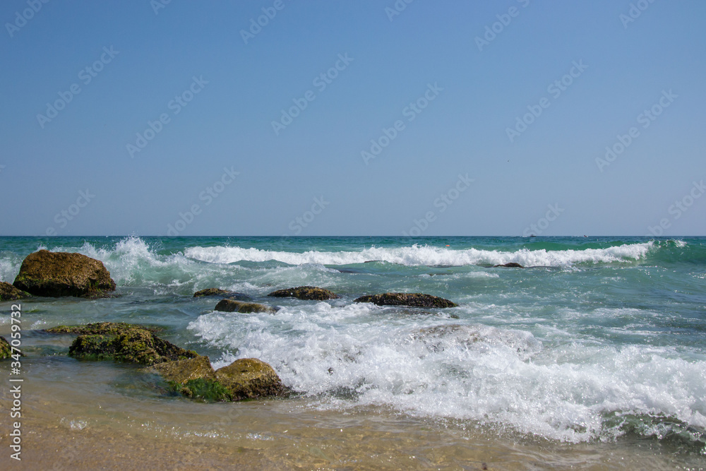 Beautiful wild beach landscape, sunny day, water waves hitting the cliffs, nature summertime scene