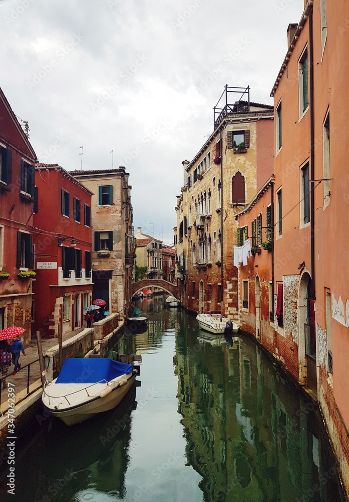 Venetian canal with boats, ancient low-rise houses, cafes and shops